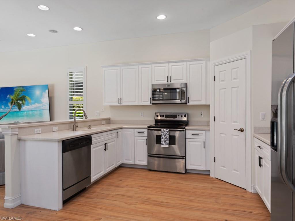 6840 Bent Grass Drive Naples, FL 34113 - Photo 5 of 21 a kitchen with stainless steel appliances a stove a sink cabinets and a refrigerator