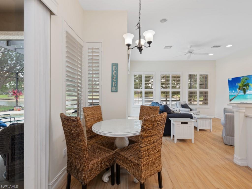 6840 Bent Grass Drive Naples, FL 34113 - Photo 8 of 21 a dining room with furniture a chandelier and wooden floor