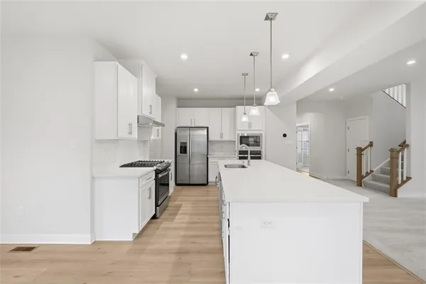 a large kitchen with kitchen island a sink a stove a refrigerator and a cabinets