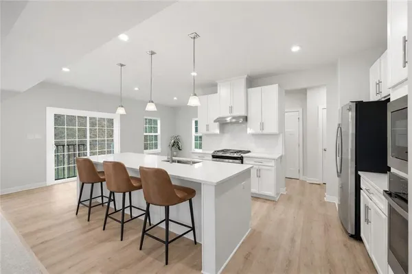 a kitchen with stainless steel appliances kitchen island granite countertop a stove a sink a refrigerator and a dining table with wooden floor