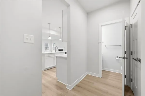 a view of a kitchen from the hallway with closet and wooden floor