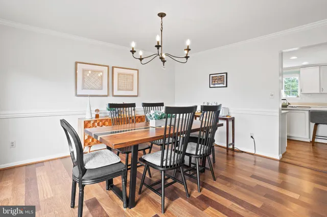 a dining room with wooden floor a chandelier a wooden table and chairs