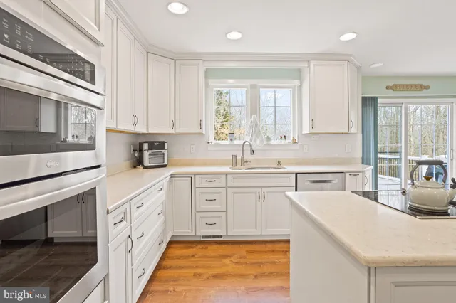 a kitchen with stainless steel appliances white cabinets a sink and a stove