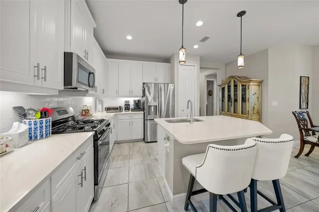 a kitchen with granite countertop a refrigerator sink and white cabinets