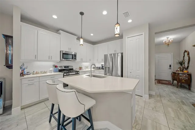 a kitchen with kitchen island a refrigerator stove and white cabinets with wooden floor