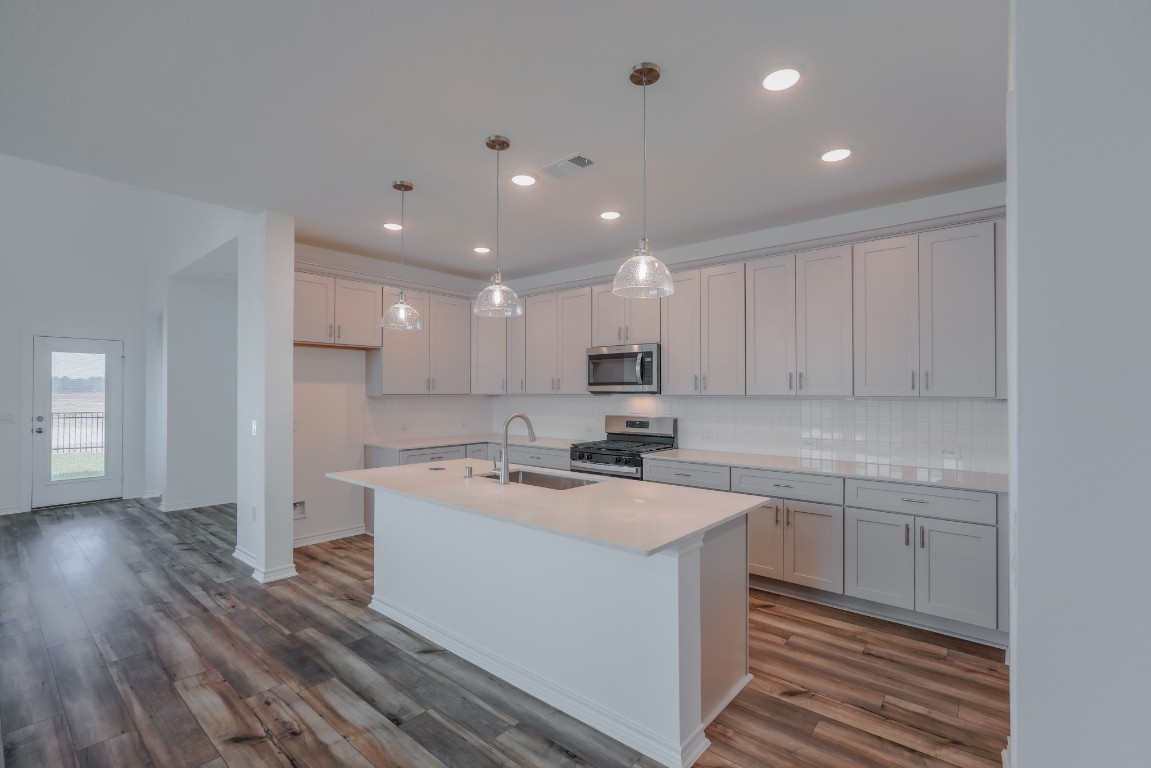 15135 Wild Gully Way Conroe, TX 77302 - Photo 5 of 42 a kitchen with a sink a stove a refrigerator and white cabinets