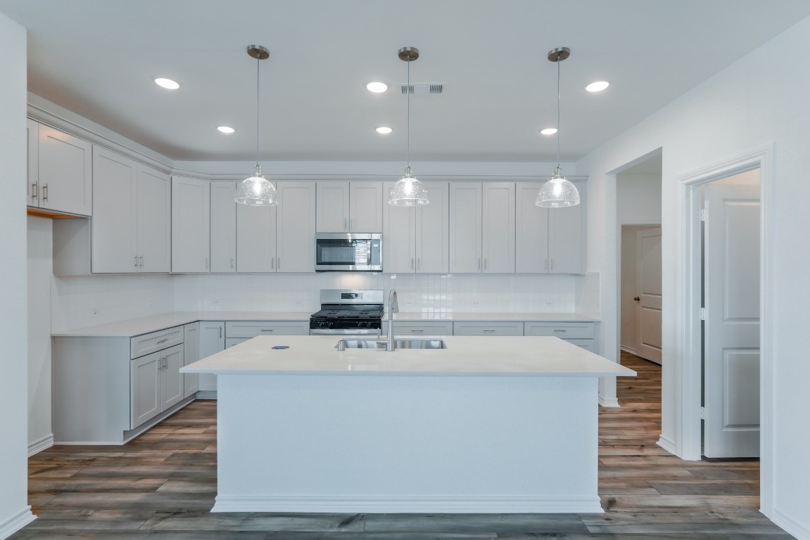 15135 Wild Gully Way Conroe, TX 77302 - Photo 10 of 42 a kitchen with kitchen island a sink a stove a refrigerator and white cabinets