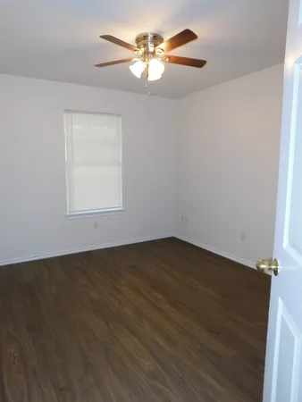 a view of a room with wooden floor and a ceiling fan