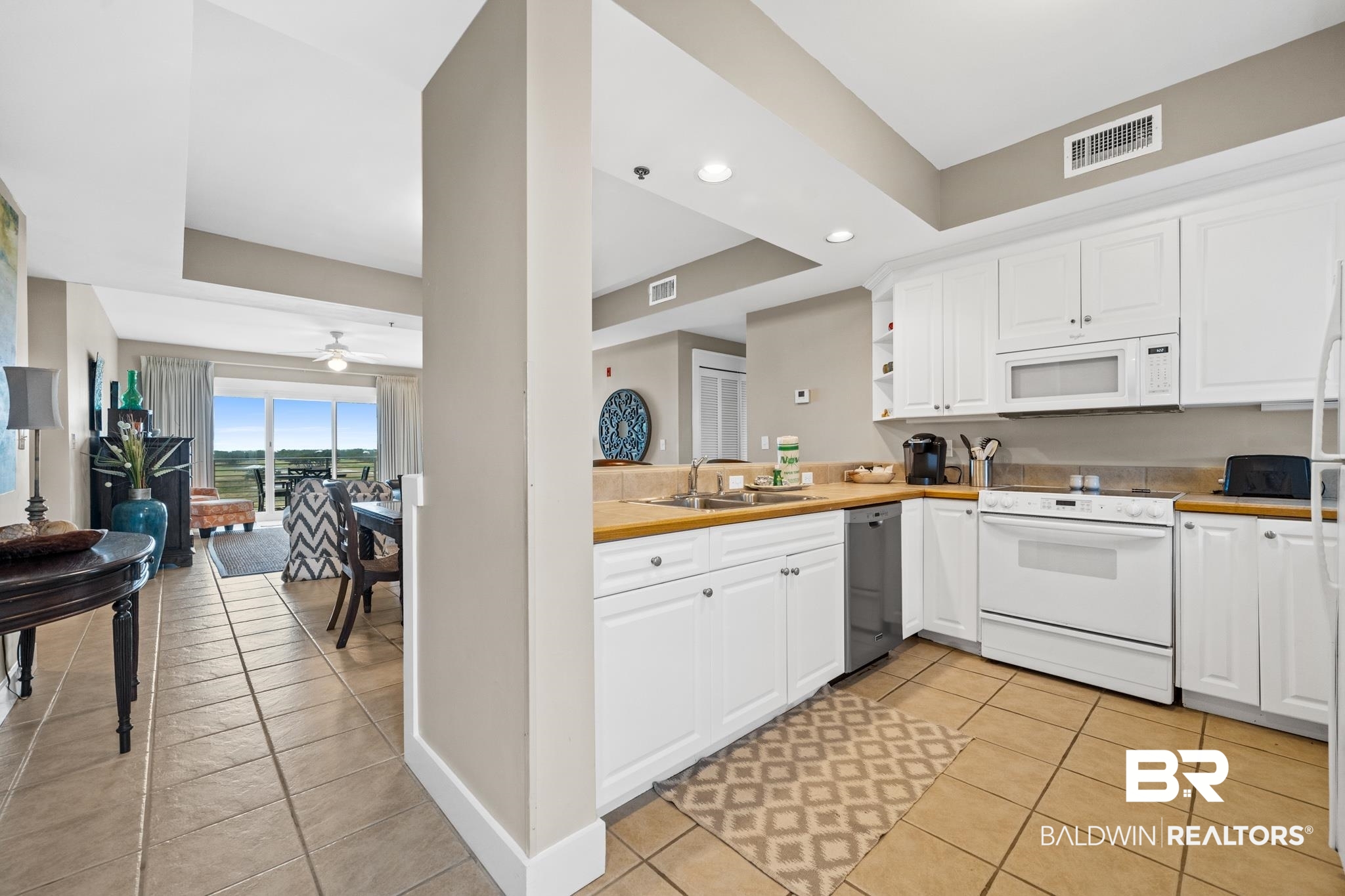 815 Plantation Road, Unit 405 Gulf Shores, AL 36542 - Photo 5 of 39 Kitchen with ceiling fan, white appliances, light tile patterned flooring, white cabinets, and sink