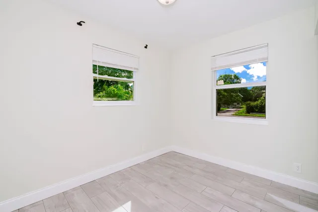 an empty room with wooden floor a ceiling fan and window