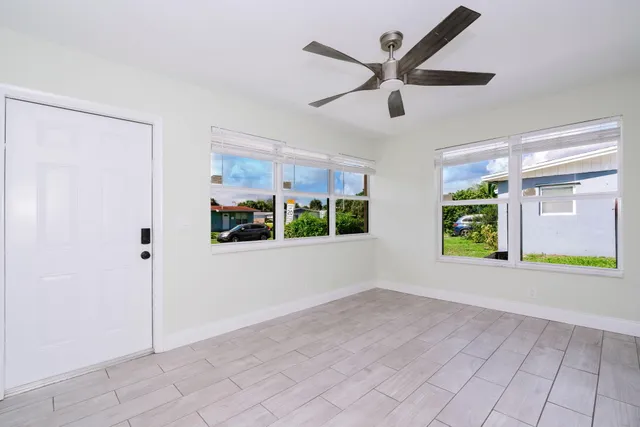 a view of an empty room with a window and kitchen view