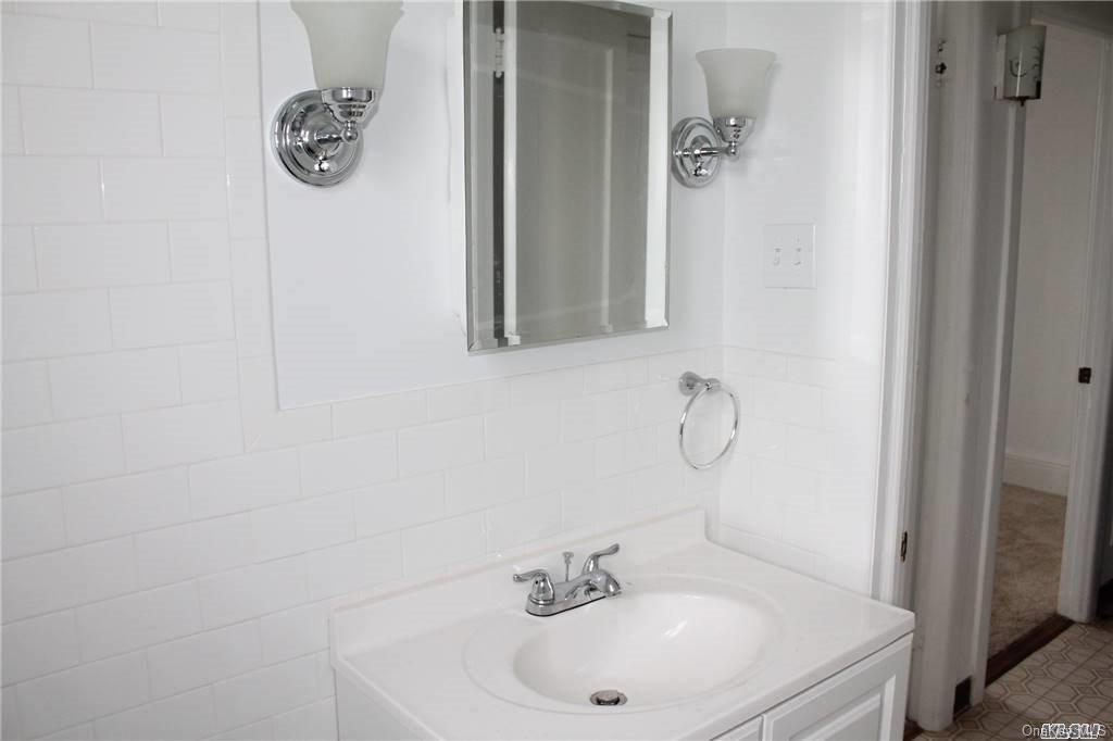 59-12 71st Street Queens, NY 11378 - Photo 20 of 26 a bathroom with a sink and mirror