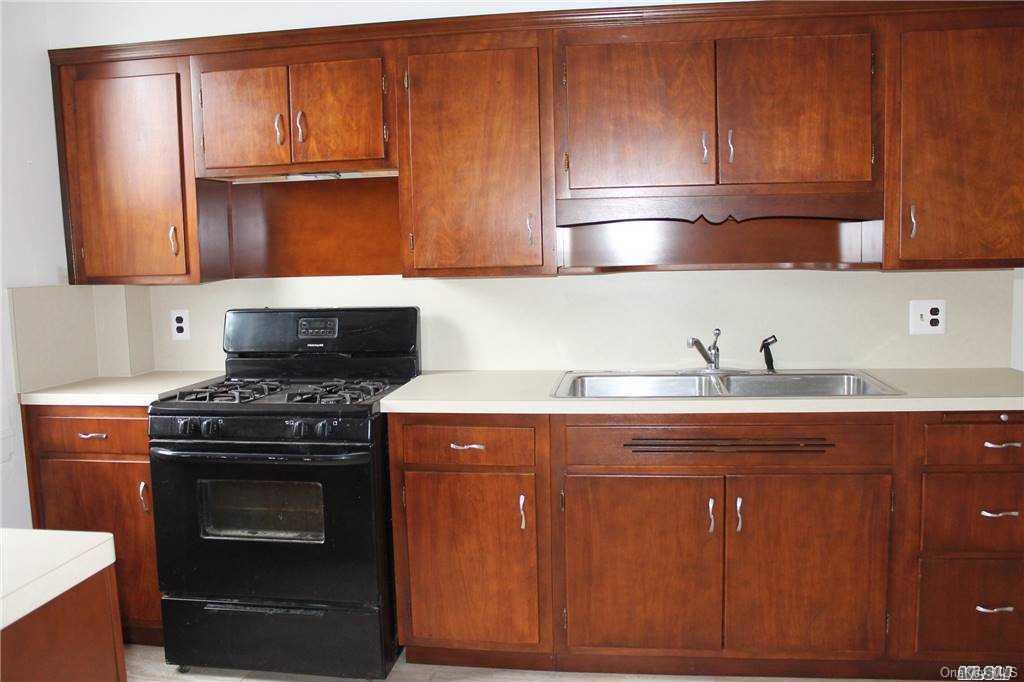 59-12 71st Street Queens, NY 11378 - Photo 9 of 26 a kitchen with granite countertop wood cabinets and stainless steel appliances