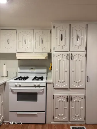 a kitchen with stainless steel appliances granite countertop a refrigerator a stove a sink and white cabinets