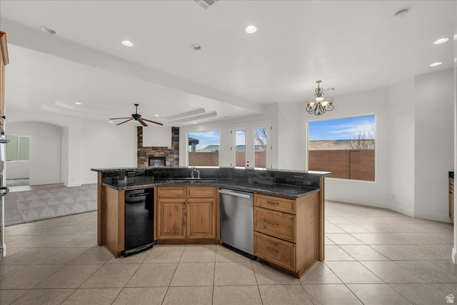 691 Rainier Drive St. George, UT 84770 - Photo 24 of 24 Kitchen featuring wood finish cabinets, a tray ceiling, open floor plan, a fireplace, and dark stone counters