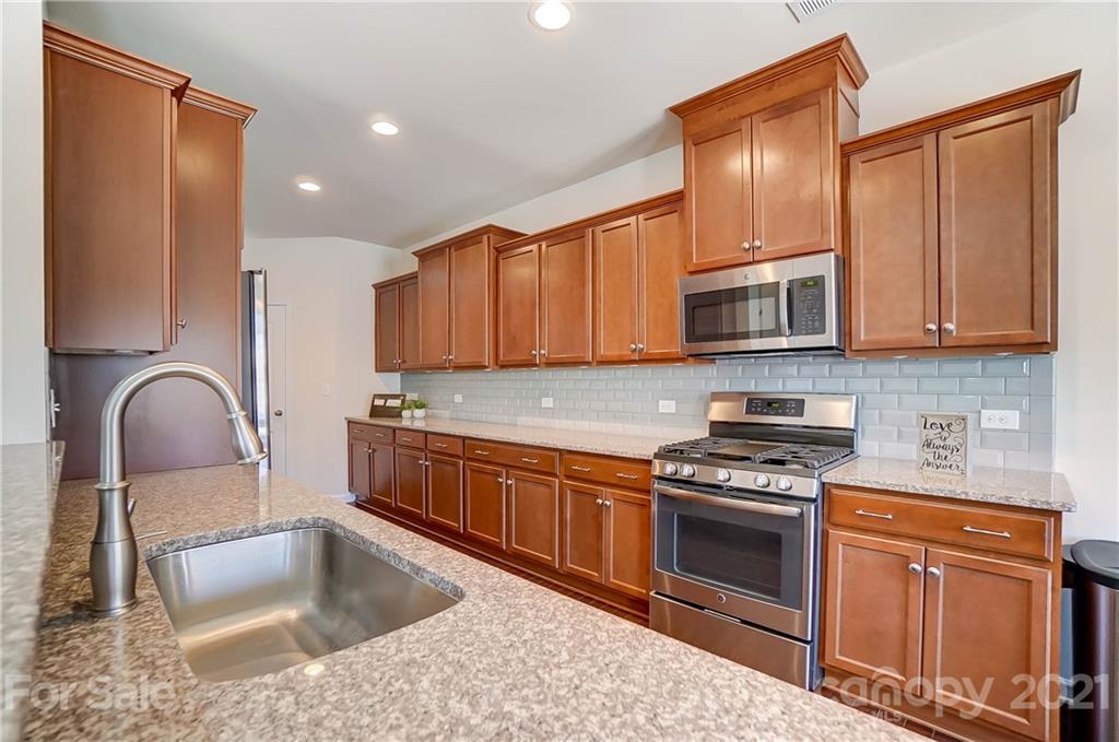 237 Butterfly Place, Unit 198 Tega Cay, SC 29708 - Photo 12 of 26 a kitchen with stainless steel appliances granite countertop a sink stove and cabinets