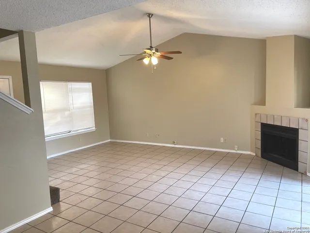 a view of an empty room with window and chandelier fan