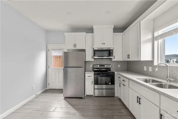 a kitchen with granite countertop white cabinets and stainless steel appliances