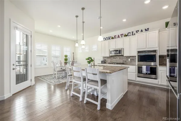 a large kitchen with cabinets chairs and wooden floor