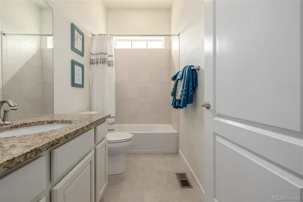 a bathroom with a granite countertop sink a toilet and shower