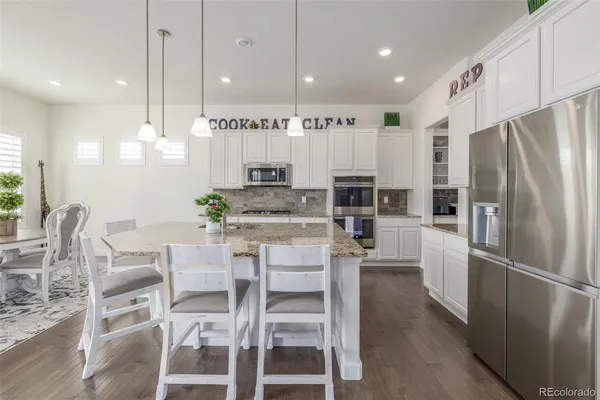 a kitchen with stainless steel appliances a dining table chairs refrigerator and sink