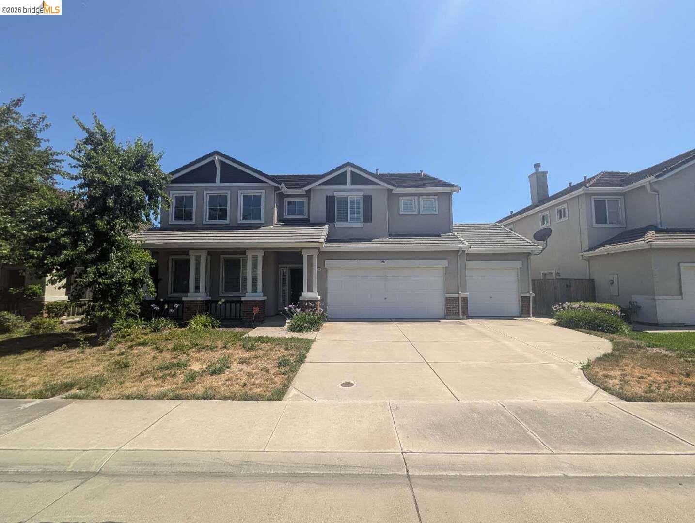 craftsman-style home featuring covered porch, concrete driveway, stucco siding, and a tiled roof