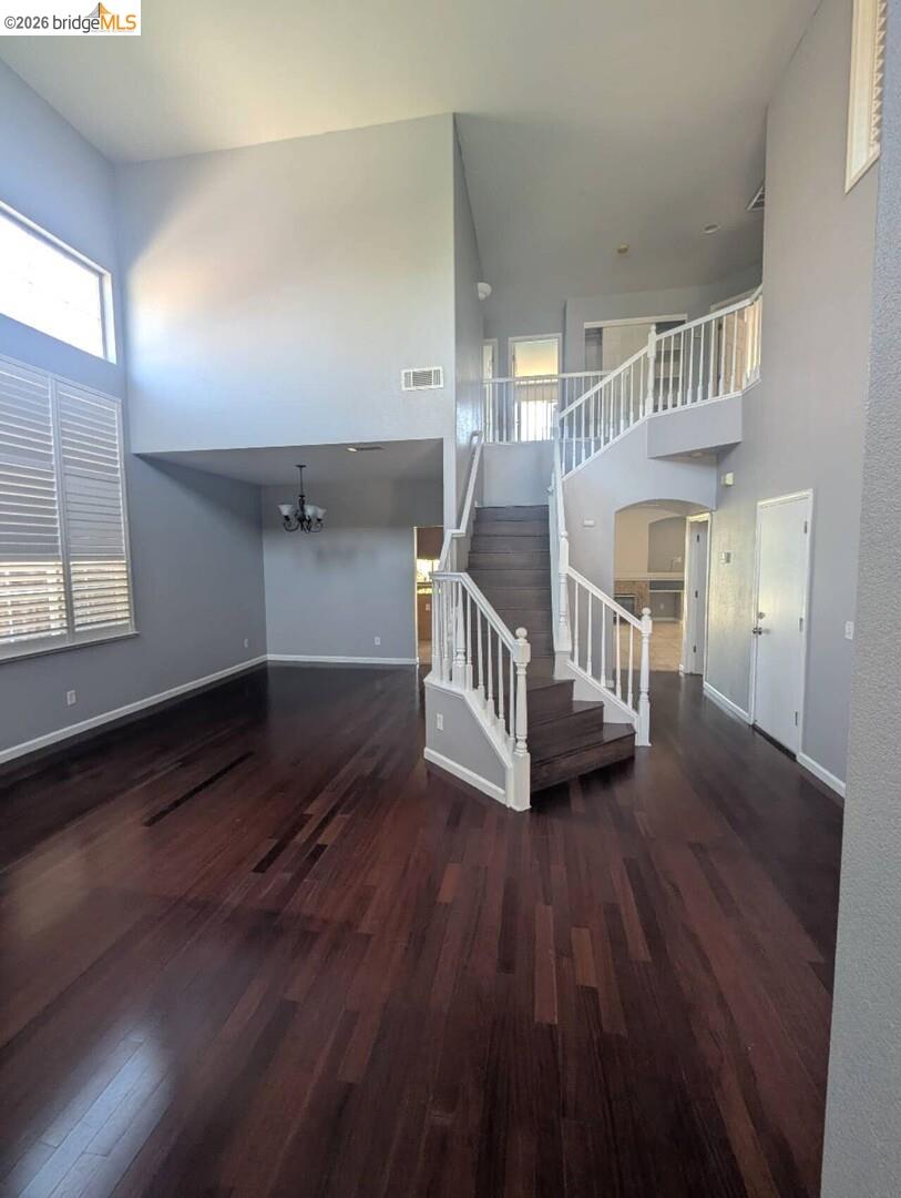 4958 Bay View Circle Stockton, CA 95219 - Photo 17 of 24 unfurnished living room featuring a high ceiling, dark wood finished floors, and a chandelier