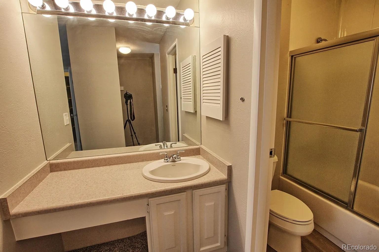 1050 South Monaco Parkway, Unit 93 Denver, CO 80224 - Photo 16 of 20 a bathroom with a sink a toilet a mirror and shower