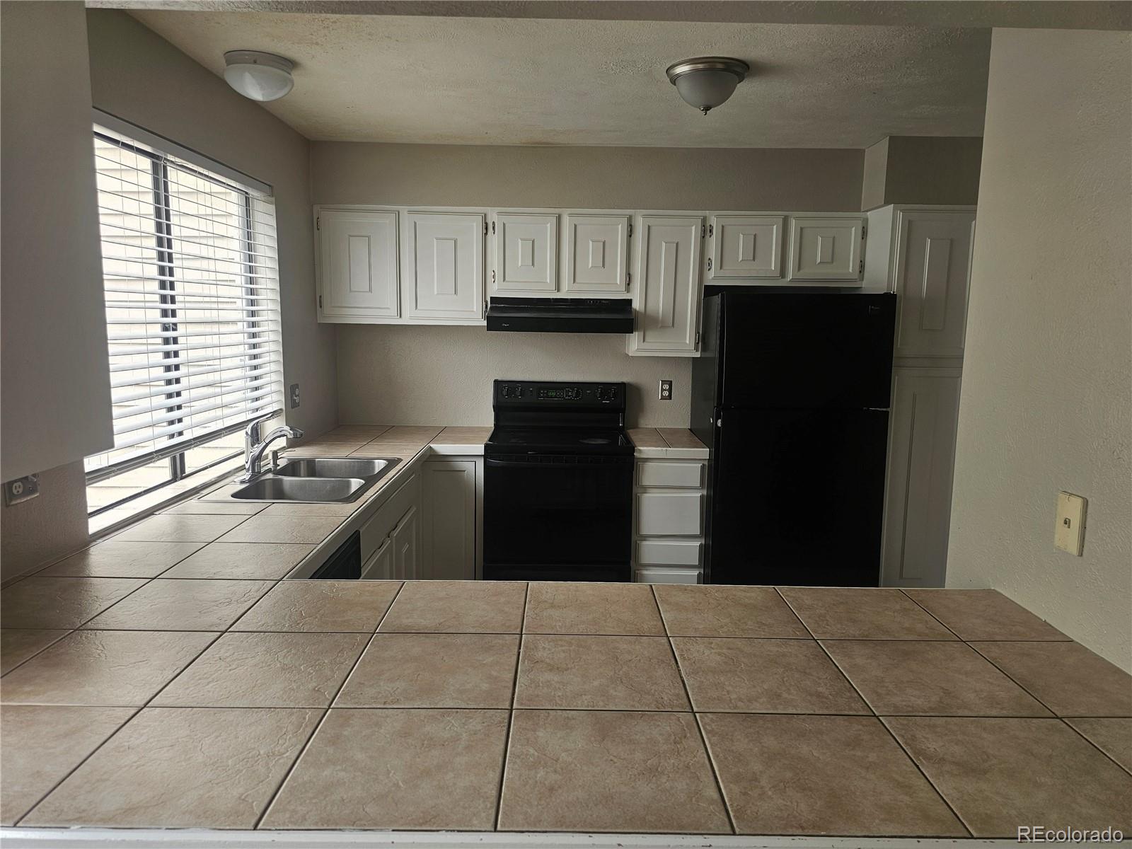 1050 South Monaco Parkway, Unit 93 Denver, CO 80224 - Photo 3 of 20 a kitchen with granite countertop a refrigerator and a stove top oven