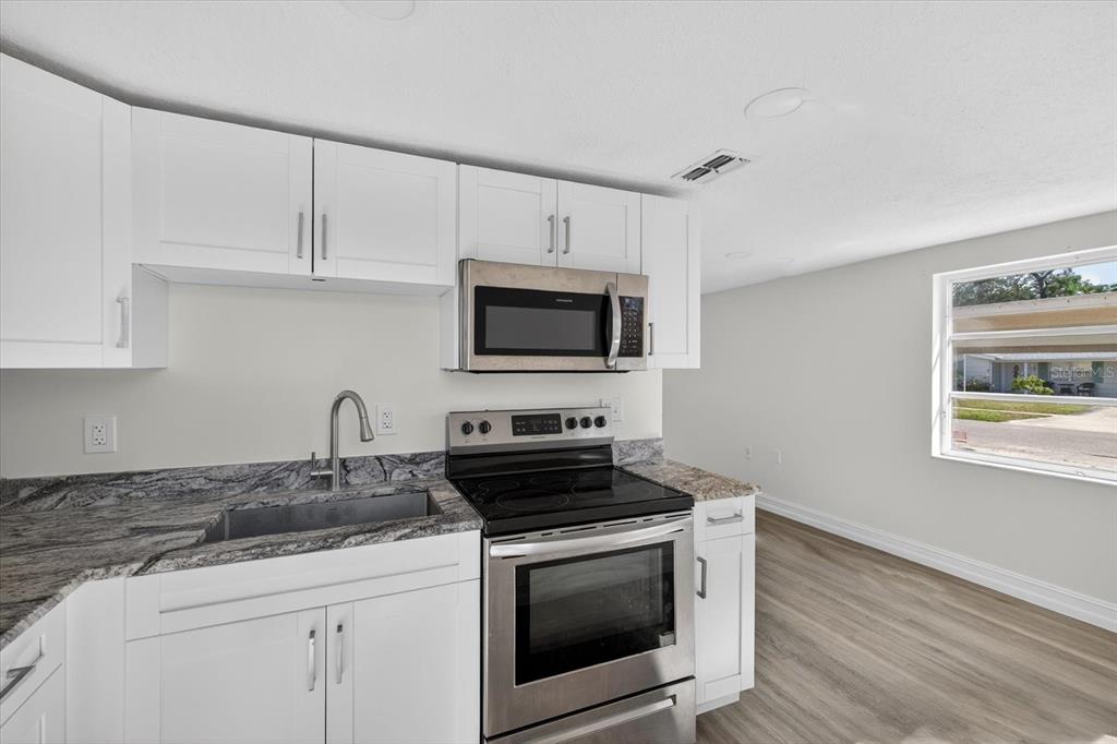 5409 Oceanic Road Holiday, FL 34690 - Photo 24 of 34 a kitchen with granite countertop a stove a microwave a sink and cabinets