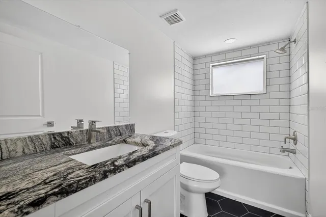 a bathroom with a granite countertop sink mirror toilet and bathtub