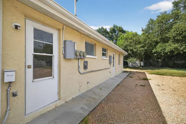 a view of house with backyard and trees in the background