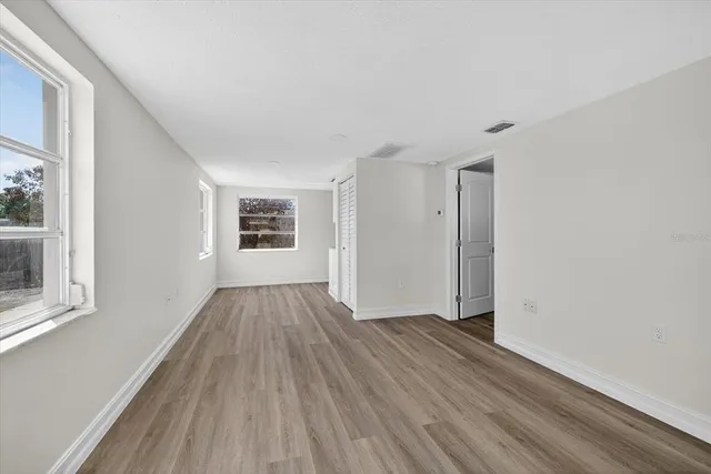 a view of an empty room with wooden floor and a window