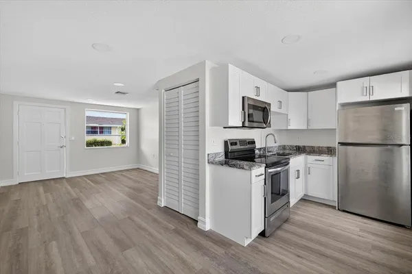 a kitchen with a refrigerator stove and wooden floor