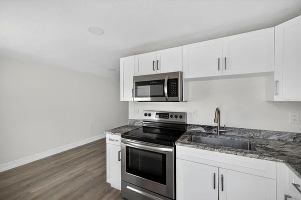 a kitchen with stainless steel appliances granite countertop a sink stove and microwave with wooden floor