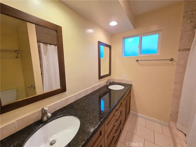 a bathroom with a granite countertop sink and a mirror