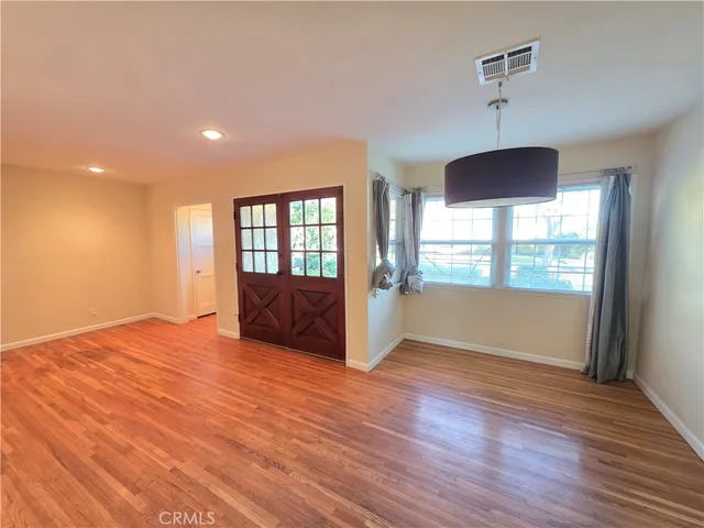 a view of an empty room with window and wooden floor
