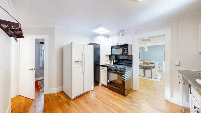a view of kitchen with stainless steel appliances kitchen island refrigerator stove and wooden floor