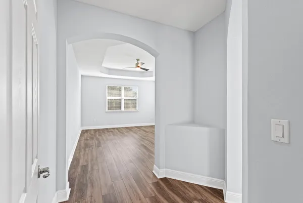 a view of an empty room with wooden floor and a window
