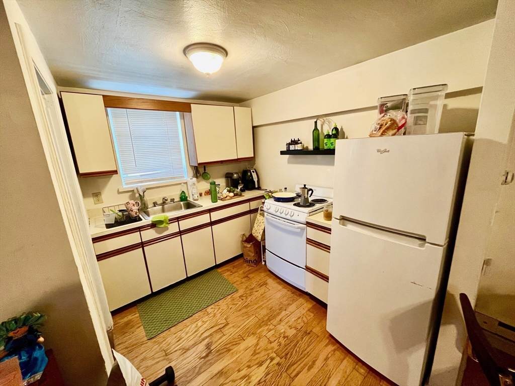 105 Chestnut Street, Unit 2B Brookline, MA 02445 - Photo 6 of 7 a kitchen with stainless steel appliances a refrigerator sink and white cabinets