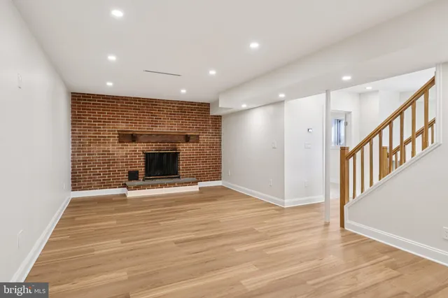 a view of an empty room with wooden floor fireplace and a window