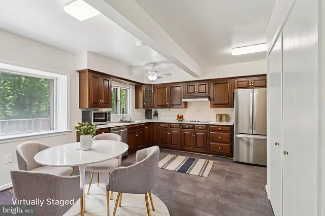 a kitchen with stainless steel appliances granite countertop a stove a refrigerator a sink a dining table and chairs with wooden floor