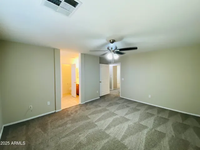 an empty room with chandelier fan and windows