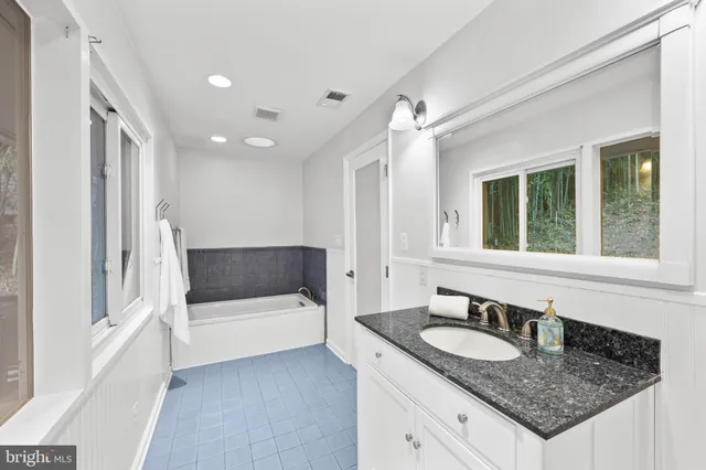 a bathroom with a granite countertop sink and a bathtub