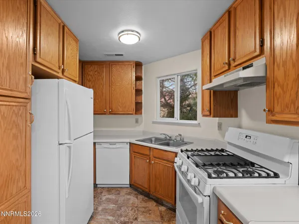 a kitchen with stainless steel appliances granite countertop a refrigerator a sink dishwasher a stove a dining table and chairs with wooden floor