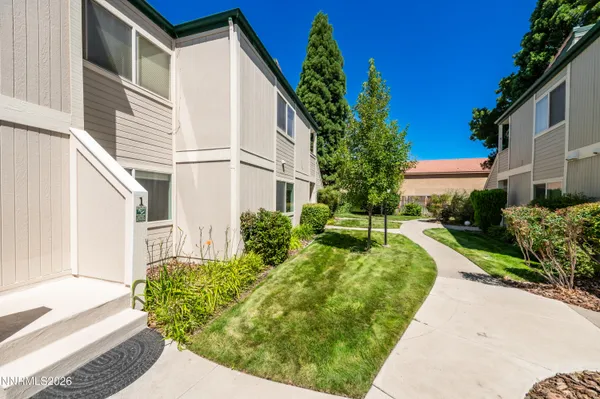 a view of a white house with a yard and potted plants