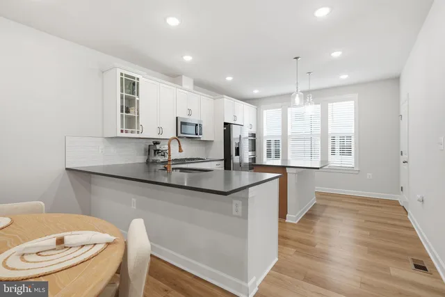 a kitchen with stainless steel appliances granite countertop a sink a stove a refrigerator cabinets and wooden floor