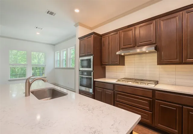 a kitchen with granite countertop a sink stainless steel appliances and cabinets