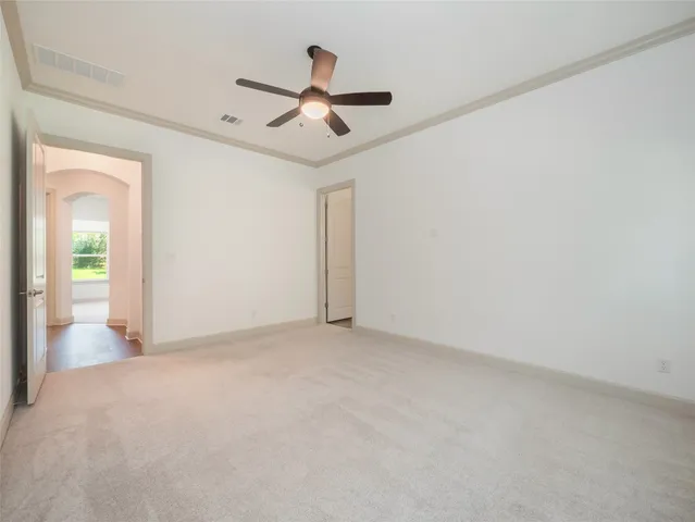an empty room with ceiling fan and windows