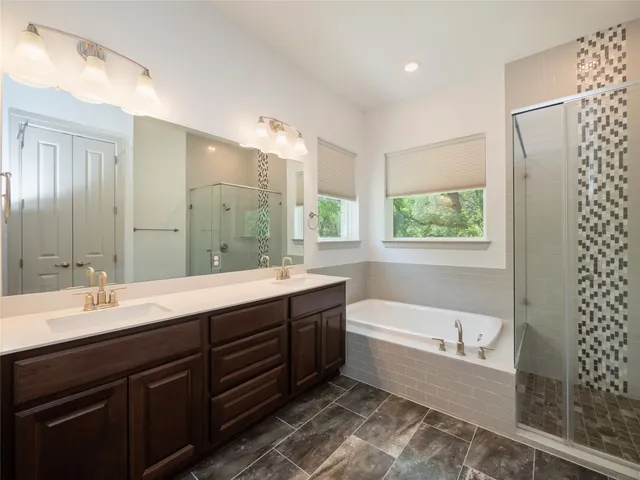 a bathroom with a tub sink double vanity granite and shower